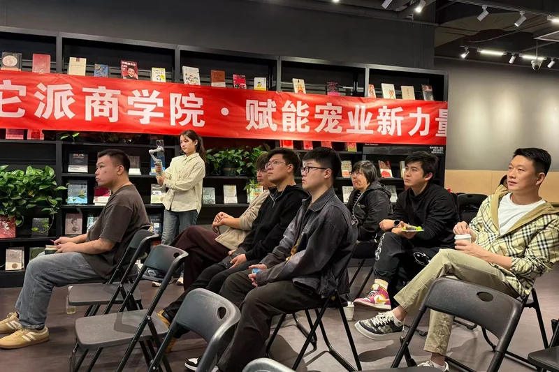参与者坐在室内参加交流活动,背后有洗它派商学院横幅
